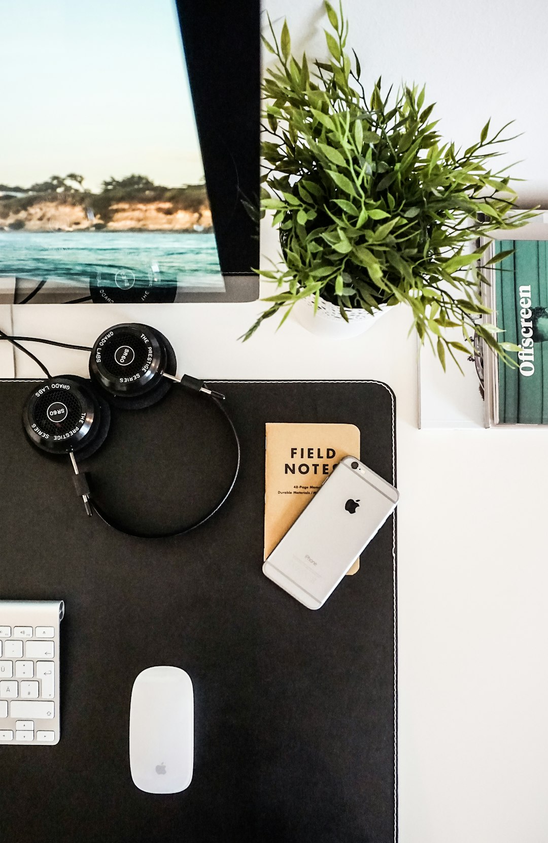 Flatlay with a small notebook by Stack Interface black headphones beside space gray iPhone on brown table